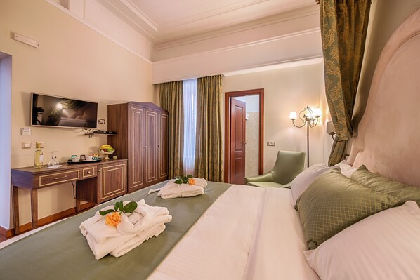 Una habitación de hotel con una cama, un escritorio con televisor, un armario y la puerta del baño.