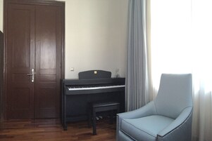 A room with a piano, a chair, and a door.