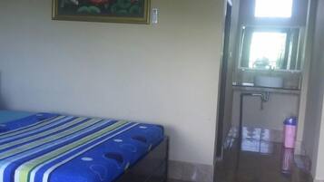 Quarto com cama, pintura, banheiro com espelho e janela.