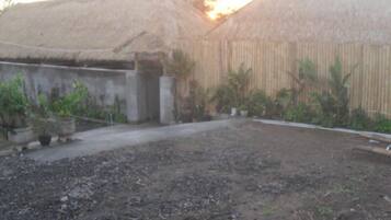 A courtyard with a dirt ground, concrete structures, and potted plants.