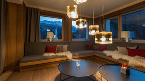 Een moderne woonkamer met een bank, twee ronde tafels en hanglampen.