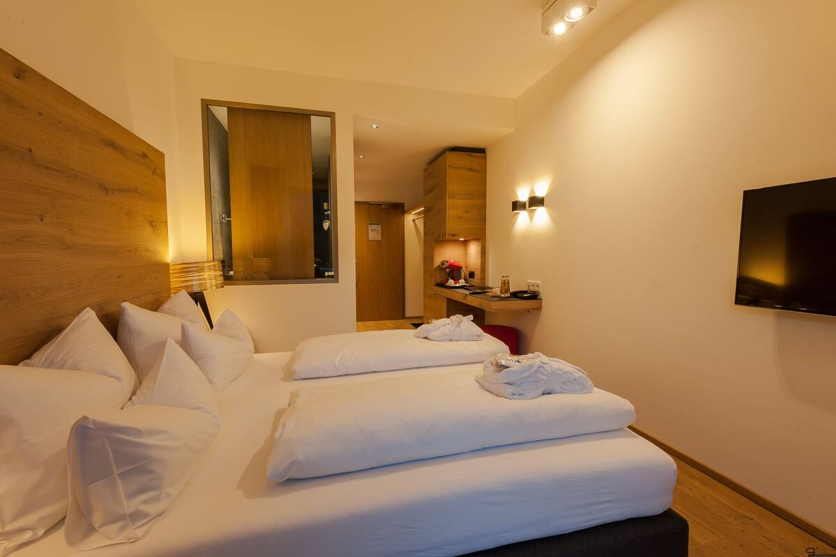 Hotelkamer met twee bedden, een houten hoofdbord, een flatscreen televisie en een bureau met lamp.