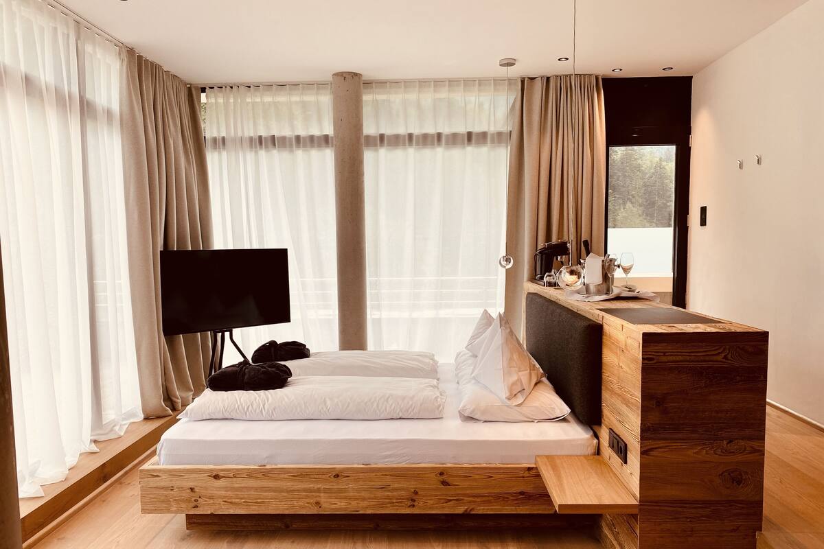 Een moderne slaapkamer met een houten bedframe, een flatscreen televisie en een houten bureau met een spiegel.