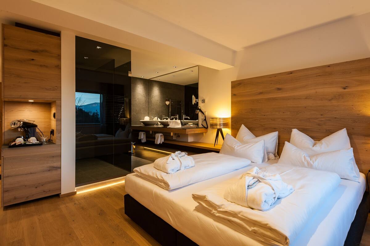 Een moderne hotelkamer met een groot bed, een houten hoofdbord, een inbouw bureau en een grote spiegel.