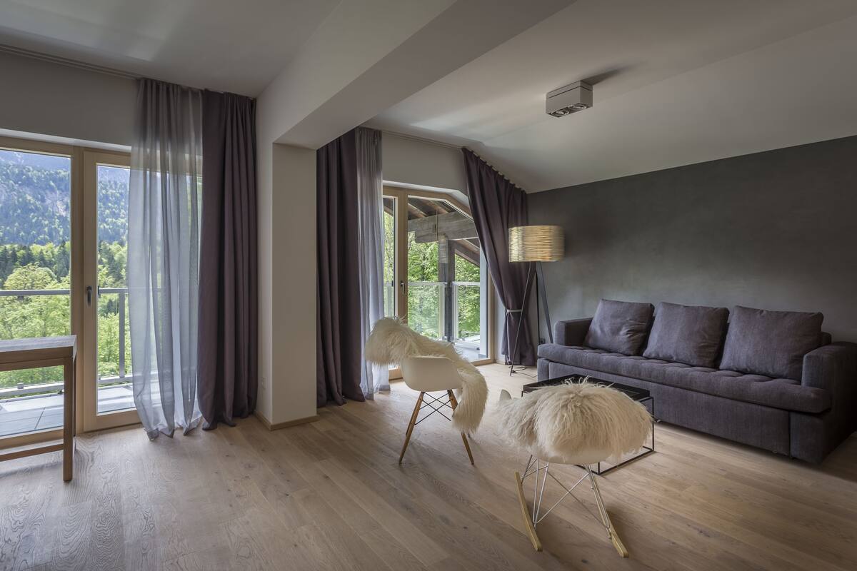 Een moderne woonkamer met een grijze bank, een witte stoel en een pluizig pouf.