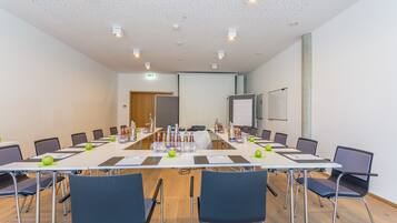 A conference room with a long table, chairs, and a projector screen.