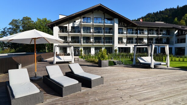 Een hotel met een houten terras, zitplaatsen buiten en een groot gebouw met meerdere balkons.