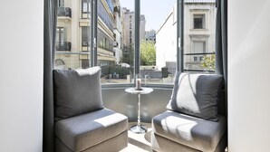 A corner seating area with two grey upholstered chairs and a small round table with a candle. - Murmuri Residence Mercader (Barcelona)
