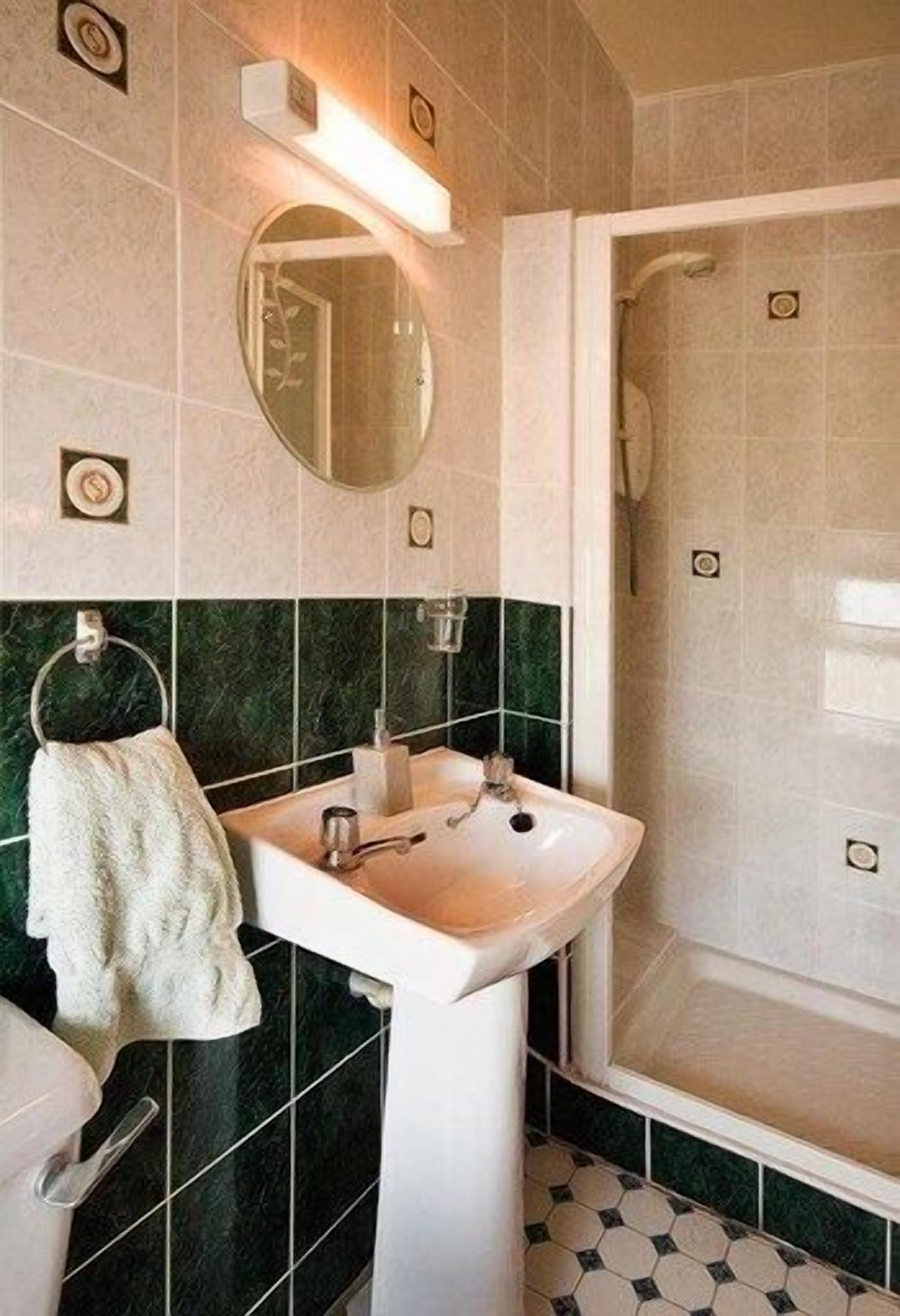 A bathroom with a white sink, a mirror, a towel rack, and a shower area.