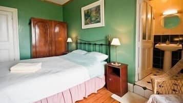 Camera da letto con un letto, comodino, lampada, armadio in legno e bagno con lavandino e doccia.