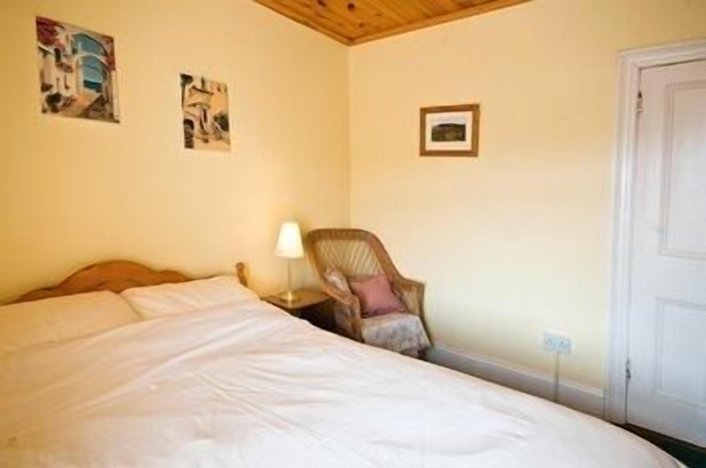 Une chambre à coucher avec un lit, une chaise et deux tableaux accrochés au mur.