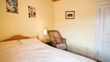 A bedroom with a bed, a chair, and two wall-mounted pictures.