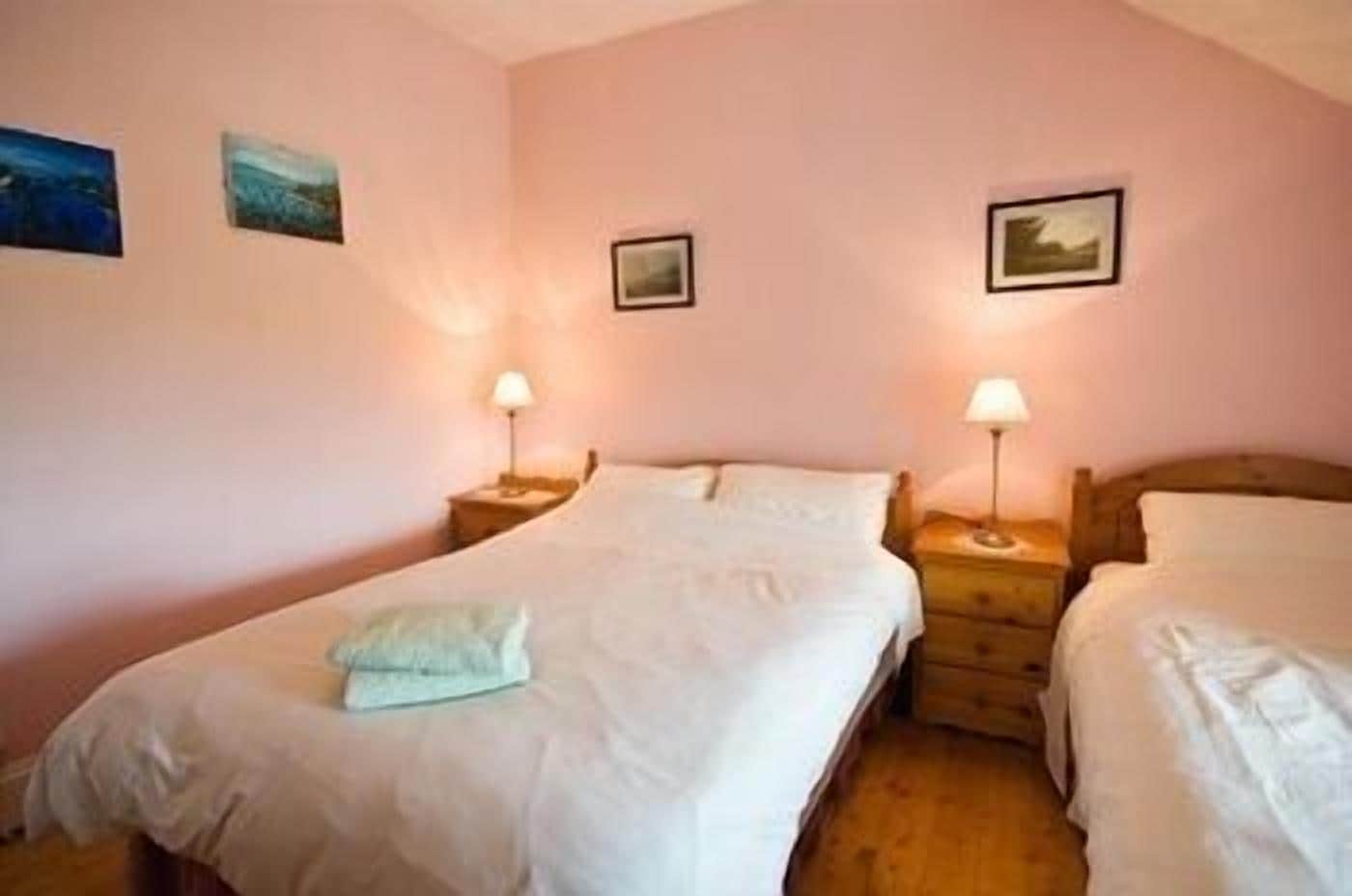 Une chambre à coucher avec deux lits, chacun doté d’une tête de lit en bois, d’une table de chevet et d’une lampe.