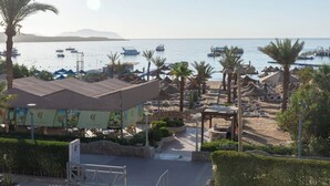 A beachside resort with a pool area, palm trees, and boats in the background. - Cataract Layalina Resort (Sharm El Sheikh)