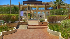 A hotel entrance with a tiled pathway leading to a gated entrance, surrounded by greenery and palm trees. - Cataract Layalina Resort (Sharm El Sheikh)
