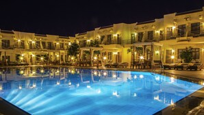 A swimming pool surrounded by multi-story buildings with balconies and outdoor seating areas. - Cataract Layalina Resort (Sharm El Sheikh)