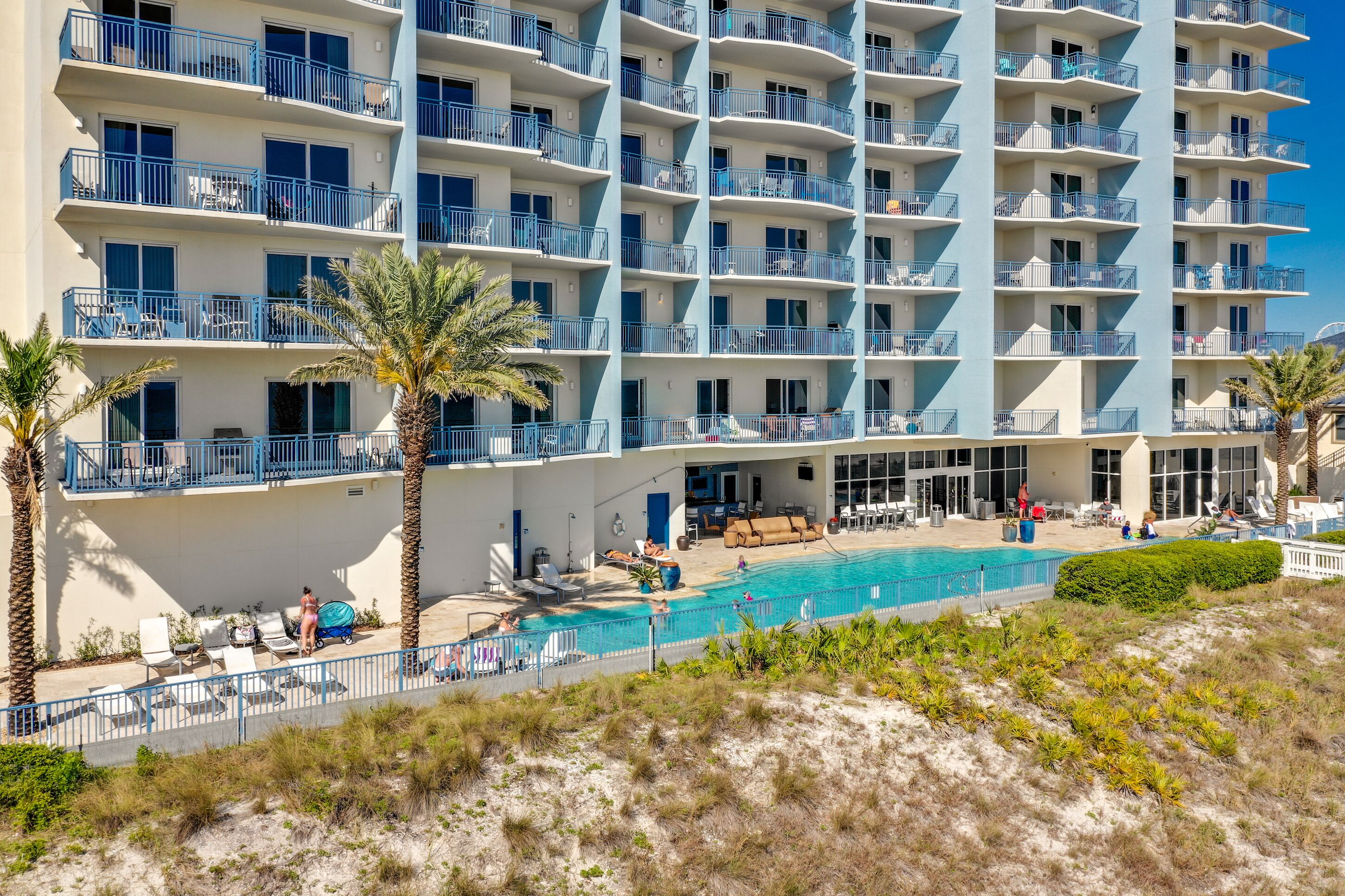 Un hotel de varios pisos con balcones, piscina y zonas de estar al aire libre.
