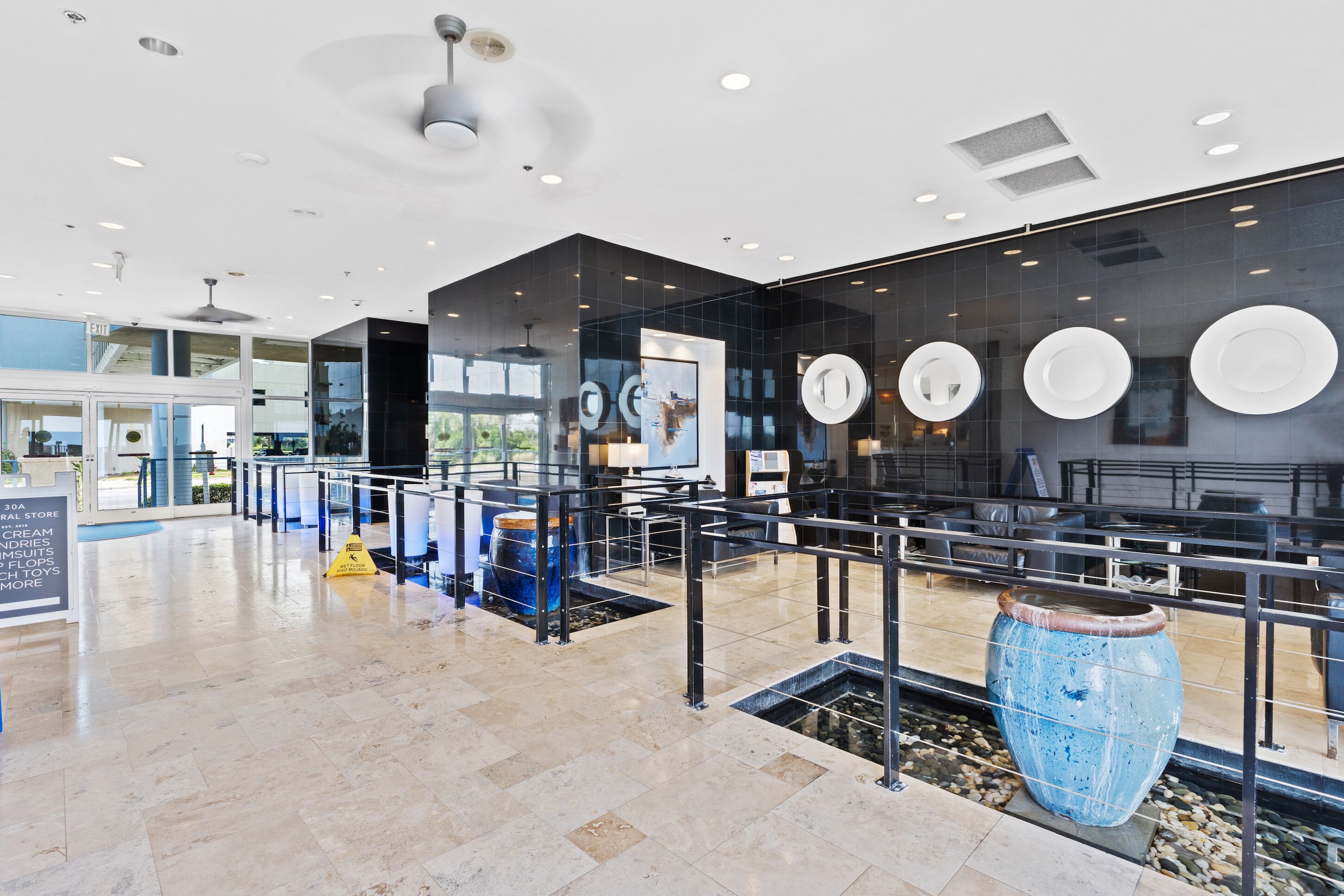 A modern interior with a glass partition, a large blue vase, and a seating area with tables and chairs.