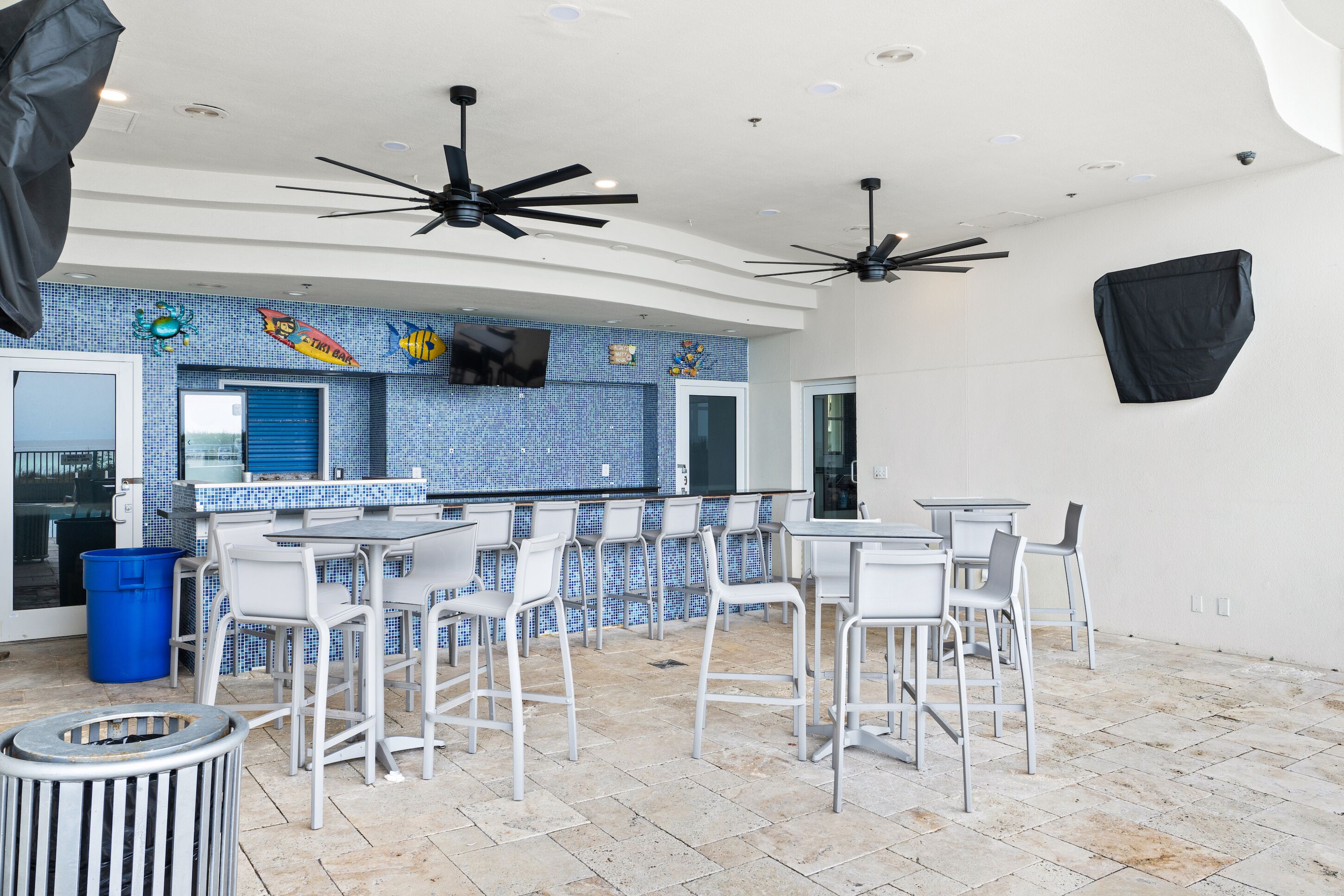 A bar area with white chairs and a blue tiled backsplash.