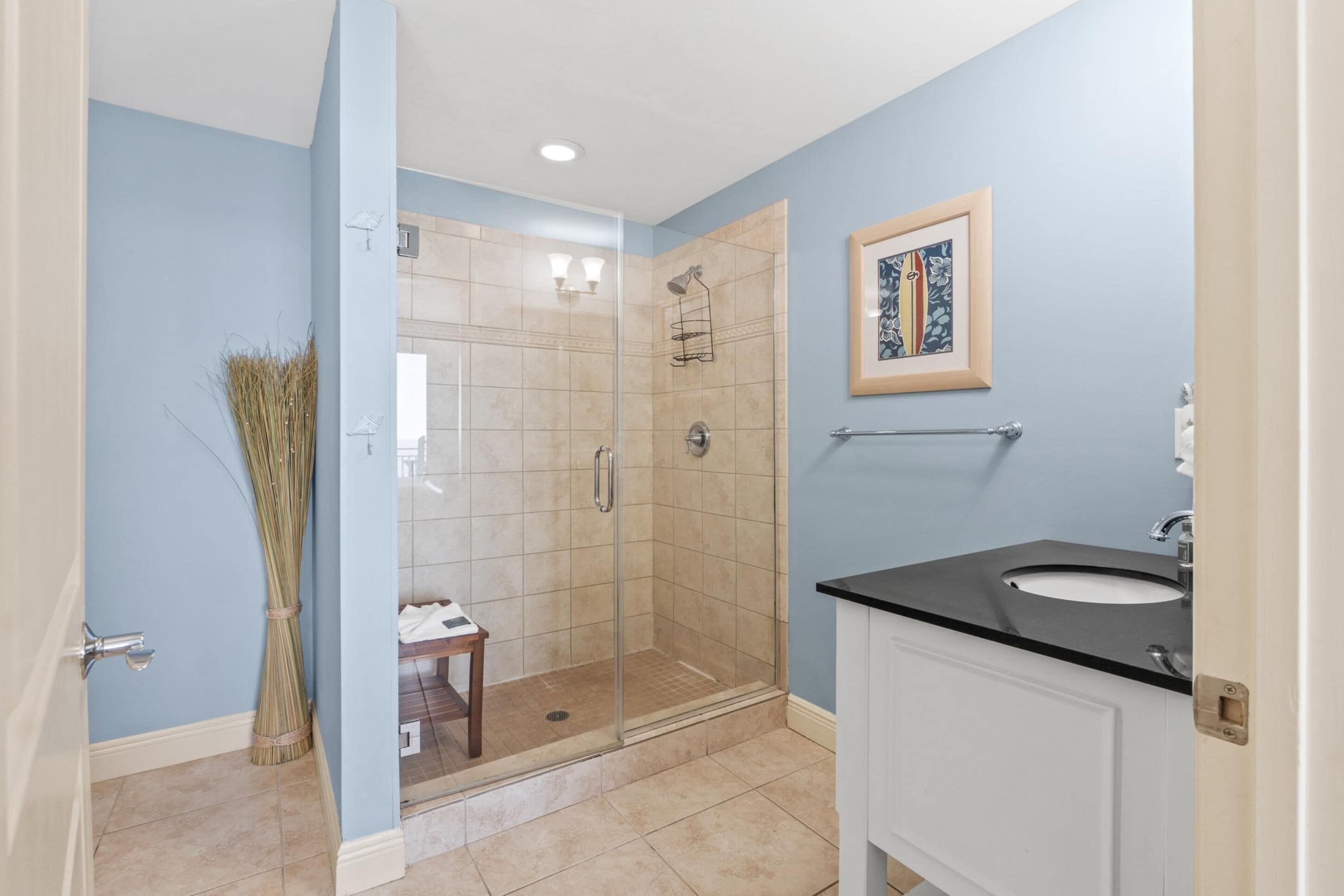 Un bagno con cabina doccia in vetro, un lavabo e un quadro appeso al muro.