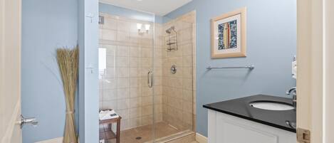 Un bagno con cabina doccia in vetro, un lavabo e un quadro appeso al muro.