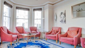 Ein Zimmer mit vier gestreiften Sesseln, einem runden Couchtisch und einem großen, blau gemusterten Teppich.