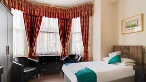 Ein Hotelzimmer mit Bett, zwei Sessel, einem Schreibtisch und einer Heizung.
