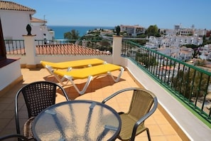 A balcony with yellow sun loungers and a glass table, overlooking a coastal town. - Hotel José Cruz (Nerja)