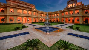 En gårdsplads med en central fontæne, omgivet af hvælvede gangstier og et bassin.