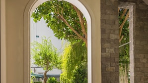 An indoor seating area with a view of a garden through an arched doorway. - Green Tea Homestay (Da Nang)