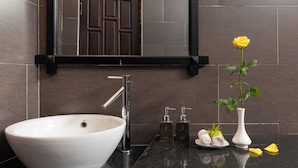 A modern bathroom with a large white sink, a mirror above it, and a vase with a yellow flower. - Green Tea Homestay (Da Nang)
