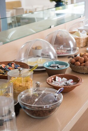A breakfast buffet with various food items and containers. - Far Out Hotel & Spa (Ios)