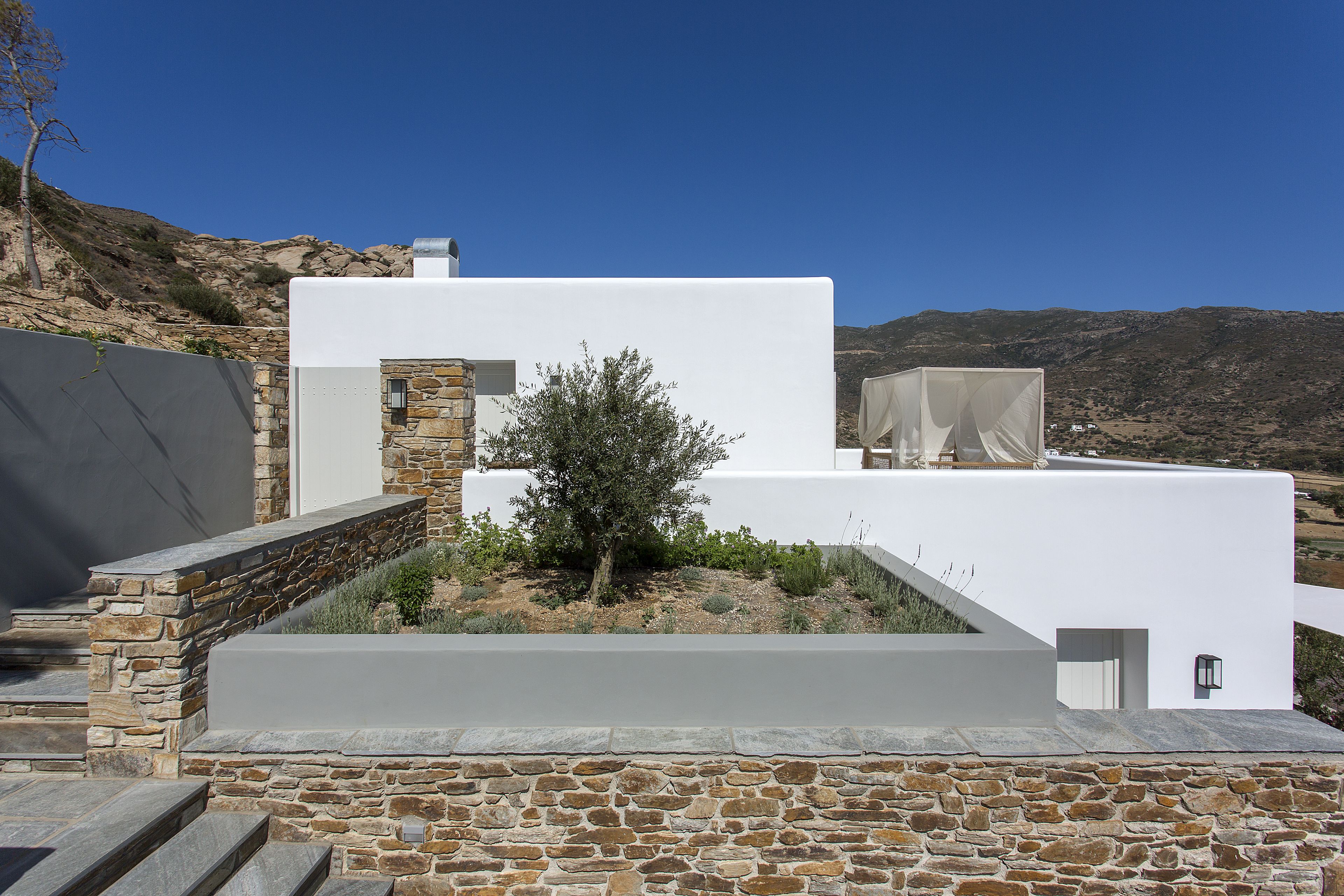 A modern building with a stone facade and a white exterior, set against a mountainous backdrop.