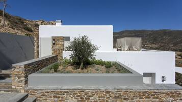 A modern building with a stone facade and a white exterior, set against a mountainous backdrop.