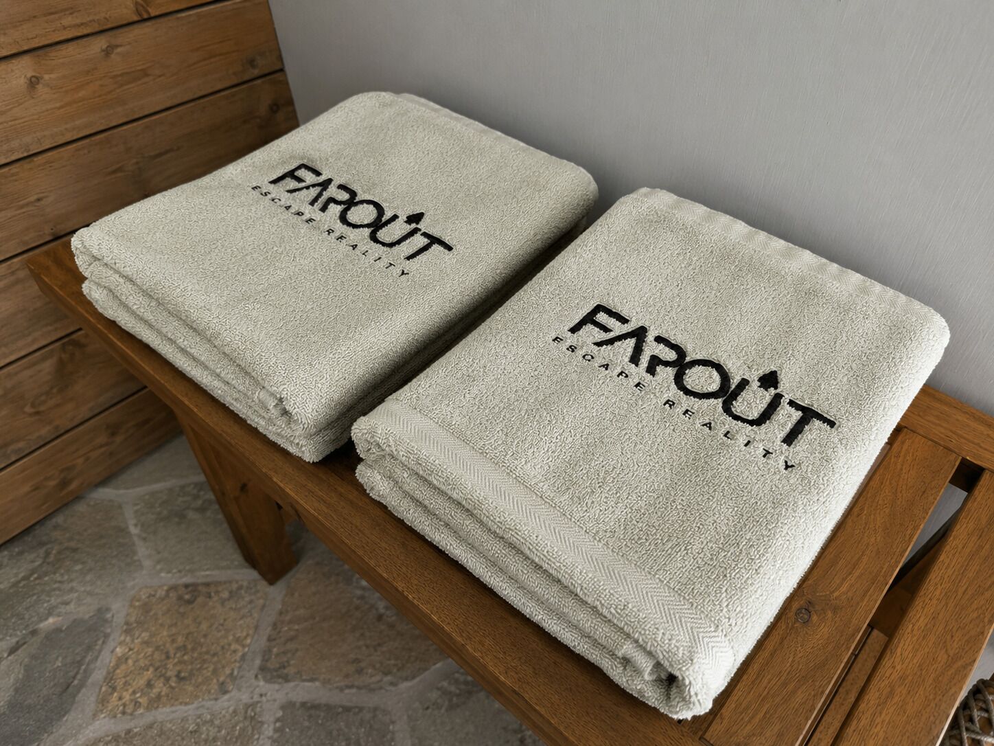 Two folded towels with 'FAROUT' branding on a wooden bench.