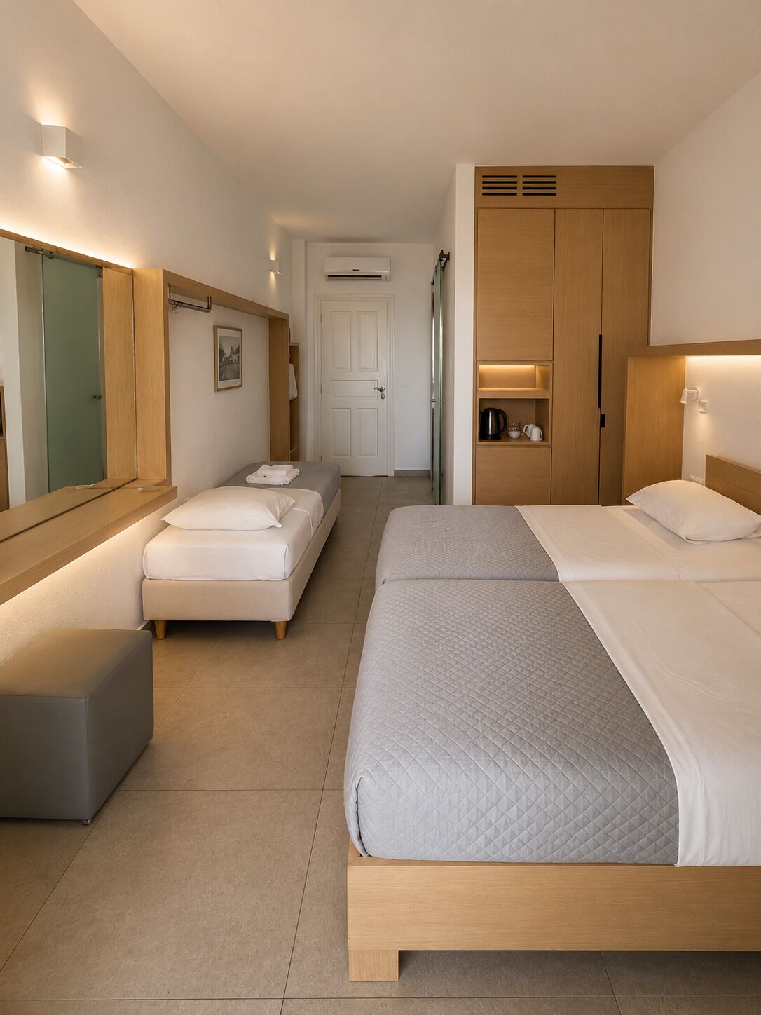 Quarto de hotel com cama, sofá, uma mesinha, guarda-roupa e espelho.
