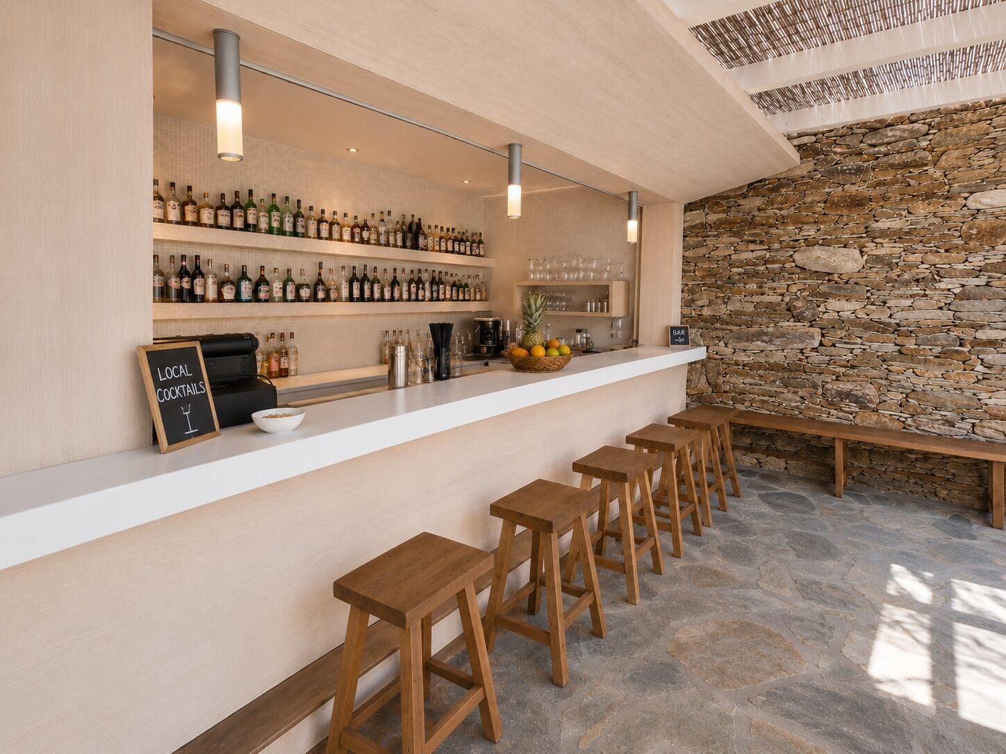 Eine Bar mit Holzhockern, einer Steinwand und Regalen voller Spirituosenflaschen.