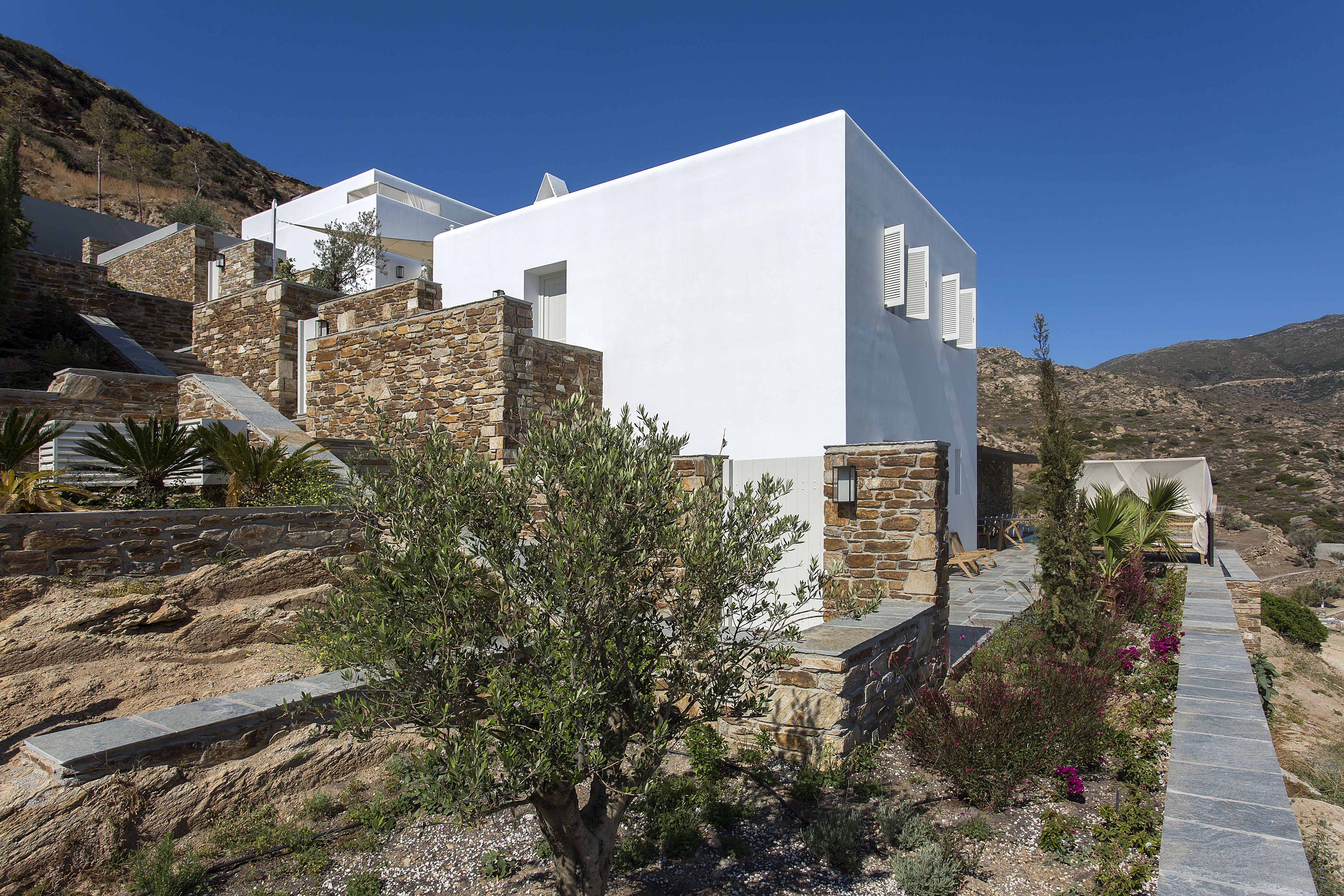 A modern building with a white facade, stone accents, and a stone pathway leading to a door.
