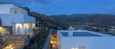 A modern building with stone steps and a flat roof, overlooking a mountainous landscape.