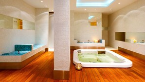 Een moderne spa-ruimte met een ruime jacuzzi, houten vloeren en spiegelwanden.