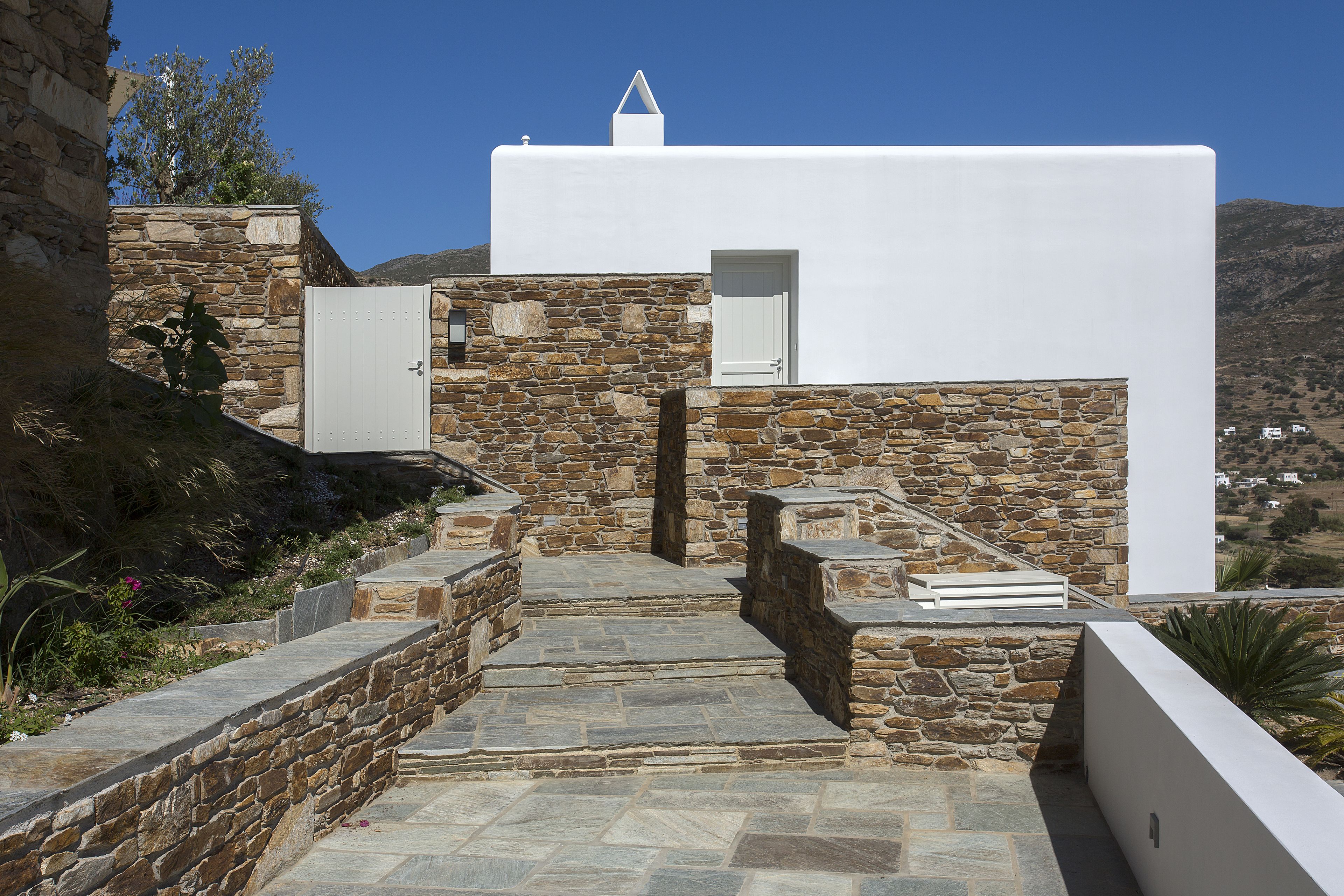 A stone-walled building with a white facade, a door, and a small window.