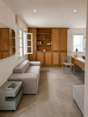 A modern living room with a sofa, a desk, and a bookshelf. - Far Out Hotel & Spa (Ios)