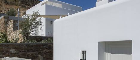 A modern building with a stone wall and a white facade, featuring a door and a light fixture.