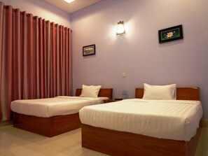 A hotel room with two single beds, a nightstand, a wall-mounted lamp, and a framed picture.
