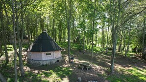 A rustic cabin surrounded by trees, with a picnic table and a fire pit in the clearing. - High Parks (Bedale)