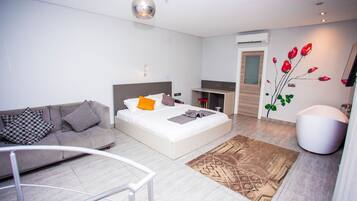 Un dormitorio moderno con una cama, un sofá, una mesita y un adorno en la pared.