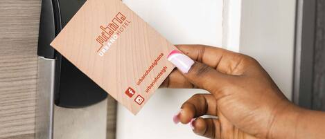 A hand holding a business card with the text "URBAN HOTEL" and social media icons.