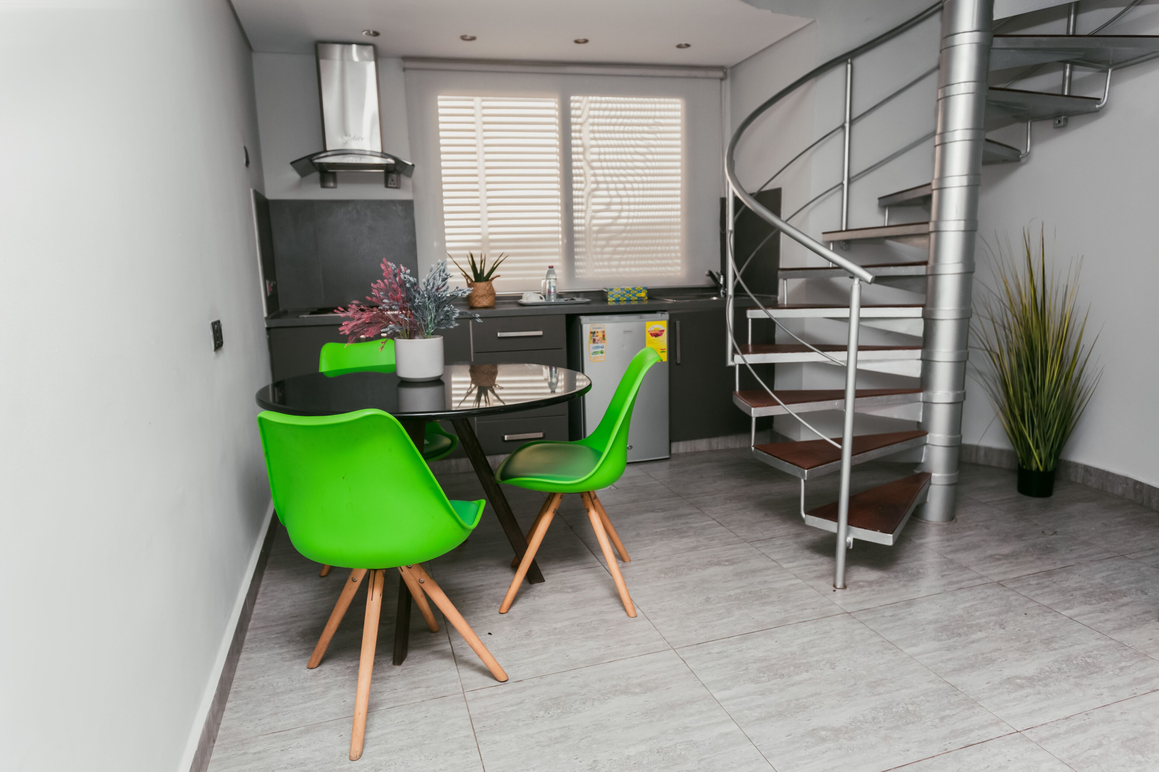 Una cocina moderna con comedor, una escalera y una planta en maceta.