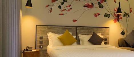A hotel room with a bed, two bedside tables, a wall-mounted telephone, and a decorative floral mural.