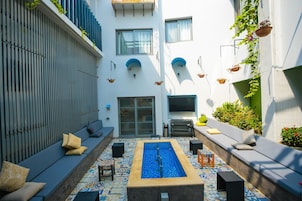 A courtyard with a pool, seating areas, and a modern architectural design.
